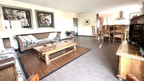 Ett rymligt vardagsrum med en soffa, ett soffbord och en matplats med stolar.