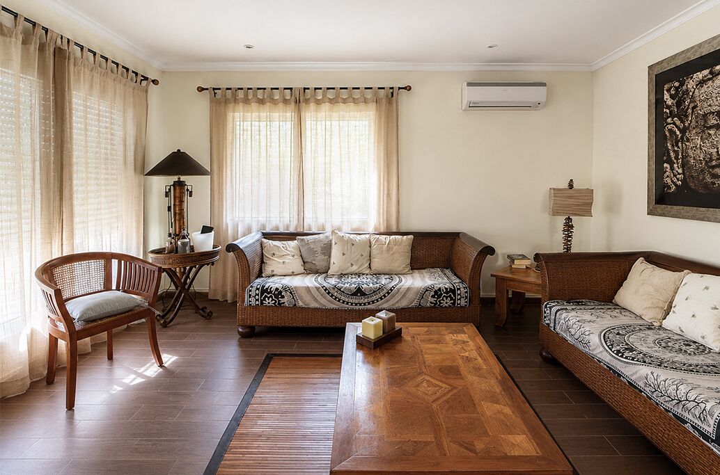 Un salon comprenant un canapé, deux fauteuils, une table basse, une lampe et un tableau accroché au mur.