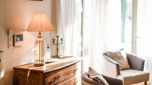 Une pièce comprenant une commode en bois, une lampe, un tableau encadré accroché au mur et une fenêtre avec des rideaux.