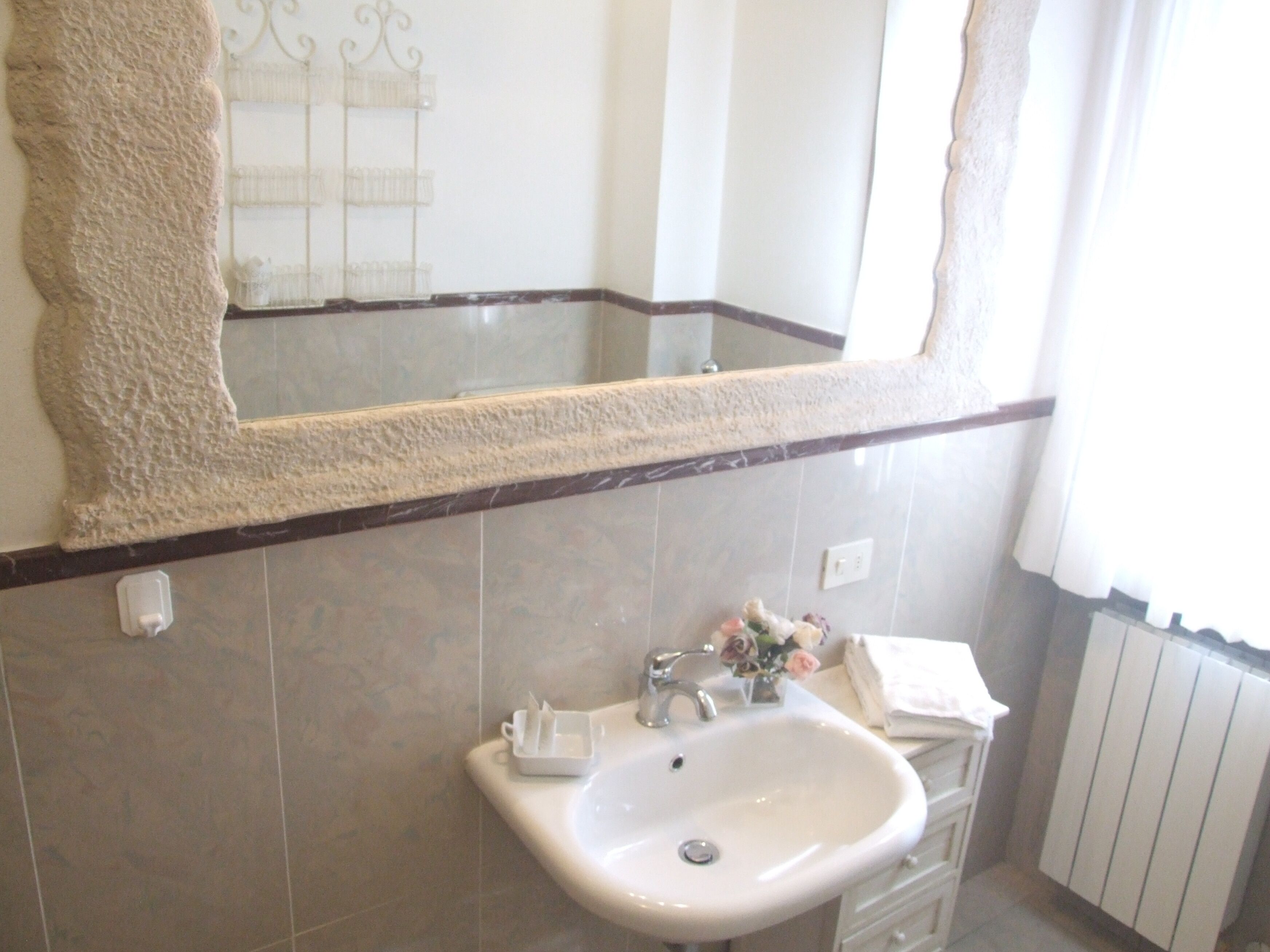 A bathroom with a large mirror, a sink, and a towel rack.