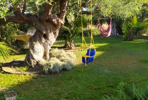 Un jardín con un columpio, una hamaca y un árbol.