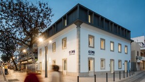 Un edificio moderno con el letrero "CONII HOSTEL & SUITES", que presenta una fachada blanca y limpia y un techo plano.