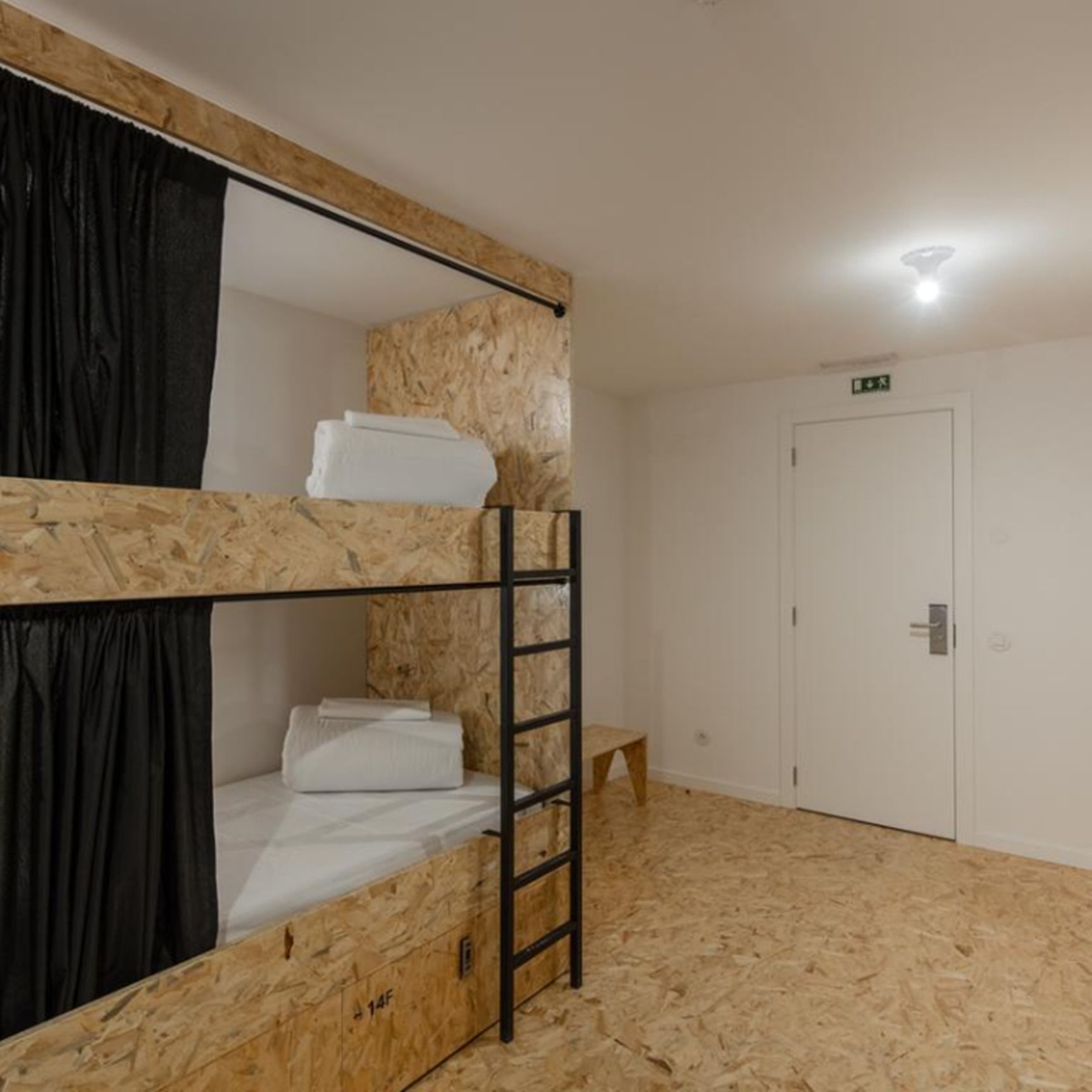 A bunk bed room with a ladder, a white door, and a small stool.