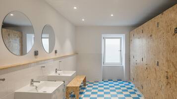 Een moderne badkamer met drie wasbakken, houten bankjes en een zwart-wit geruite vloer.