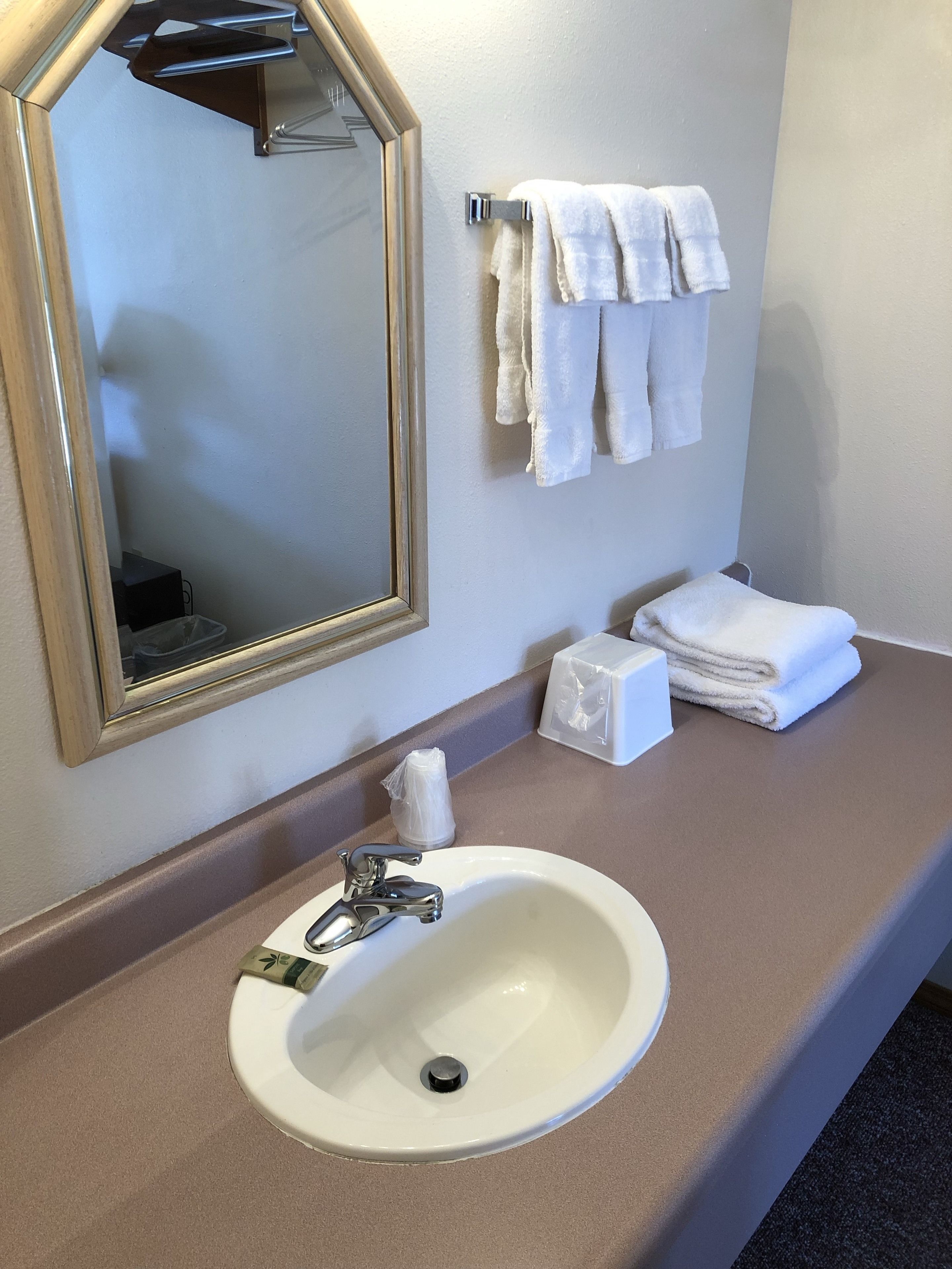 A bathroom with a white sink, a mirror, and a towel rack with folded towels.
