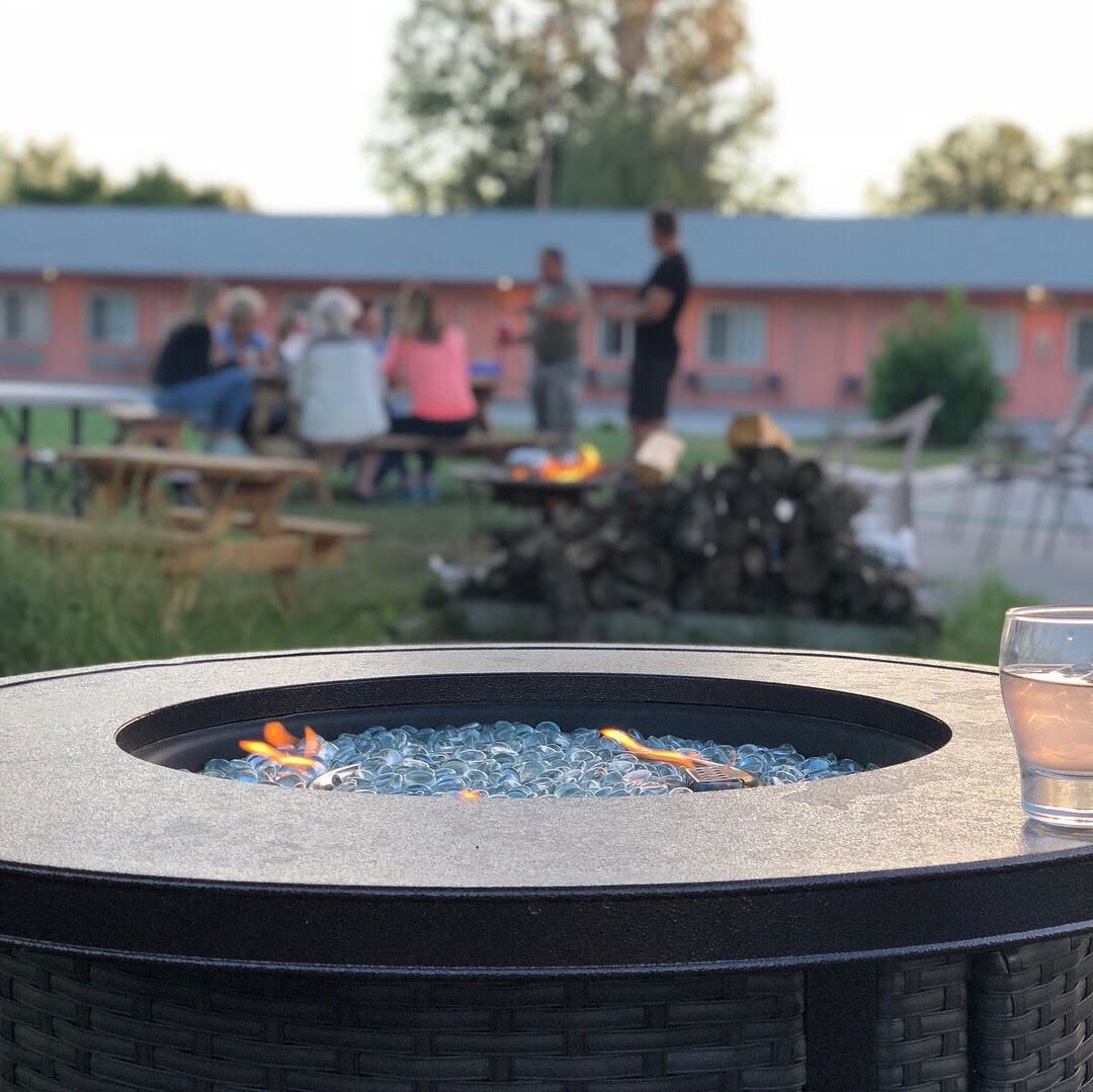 Un foyer extérieur de forme ronde, doté d’un couvercle en verre et entouré d’un bord noir tressé.