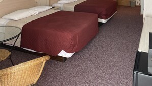 A hotel room with two beds, a desk, a chair, and a door leading to another room. - Wheels Motel (Greybull)