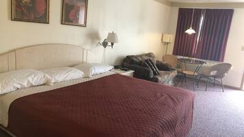 Una habitación de hotel con una cama grande, dos lámparas de pared, un escritorio con una silla y dos cuadros enmarcados.