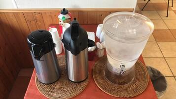 Uma mesa com cafeteira, termo e dispensador de água.
