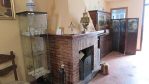 Ein Zimmer mit Kamin aus Backstein, einer Glasvitrine und einem Holzstuhl.
