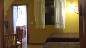 Ein Zimmer mit einem hölzernen Bett, einem Stuhl, einem Vorhangfenster und einer dekorativen Decke.