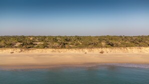A coastal landscape with a sandy beach and a forested hill in the background. - LV Premier Troia - TR1 (Grandola)