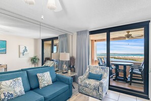 A living room with a sofa, armchairs, a table, and a view of the beach through large windows. - Open Concept floor plan, larger than a standard one bedroom! One free beach chai (Destin)