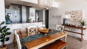 A modern dining area with a wooden table, white chairs, and a large woven chandelier.