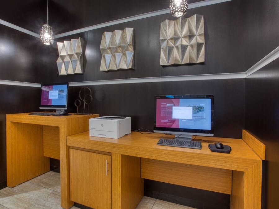 A modern office with two desks, each with a computer, printer, and keyboard.
