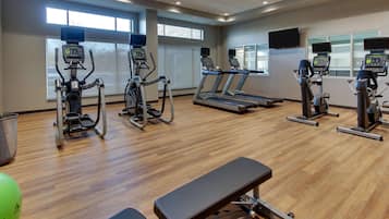 A gym with treadmills, elliptical machines, and a bench.