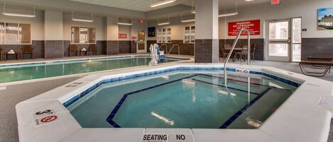 An indoor swimming pool with clear signage indicating no diving allowed and seating areas.