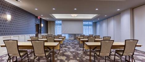 A conference room with hexagonal patterned carpet, beige chairs, and a long table.