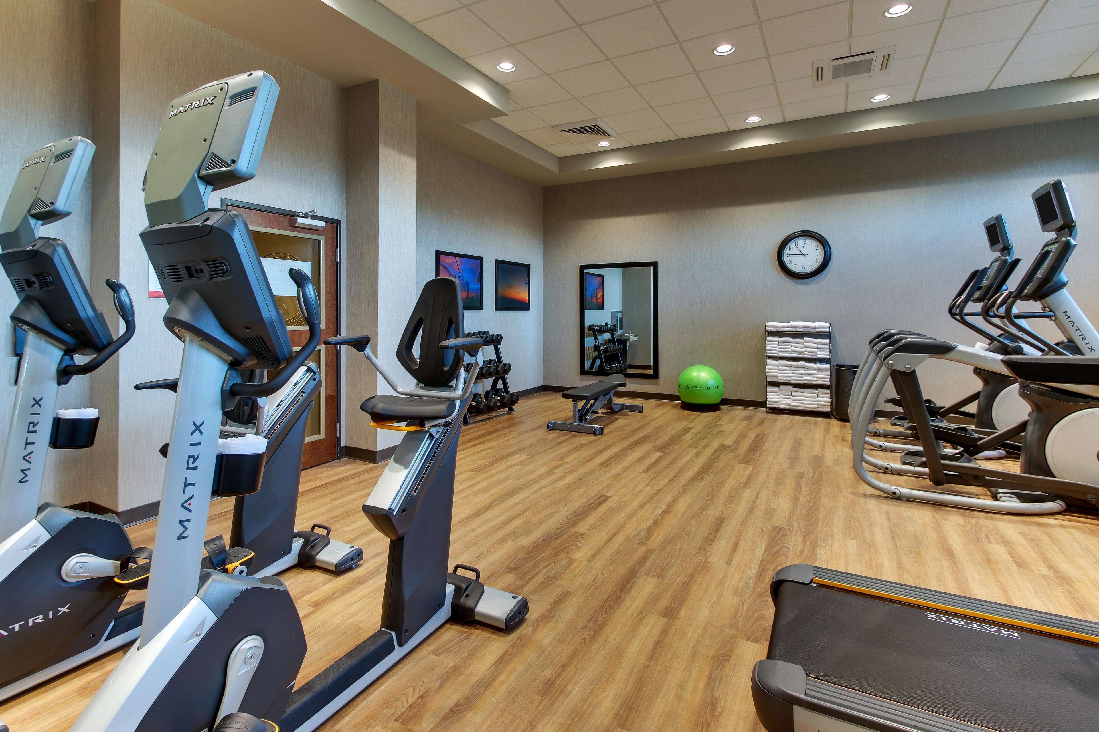 A gym with various cardio machines, a treadmill, and a mirrored wall.