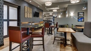 Un restaurante moderno con cabinas, mesas altas y una zona de bar.