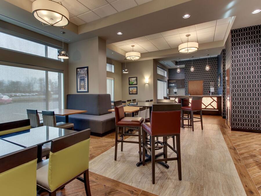 A modern hotel lobby with a seating area, a reception desk, and large windows.