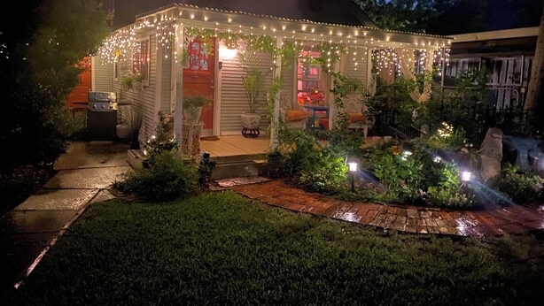 A covered outdoor area with string lights, potted plants, and a grill. - Garden Cottage, Far From The Maddening Crowd but so close to the night life! (Dallas)