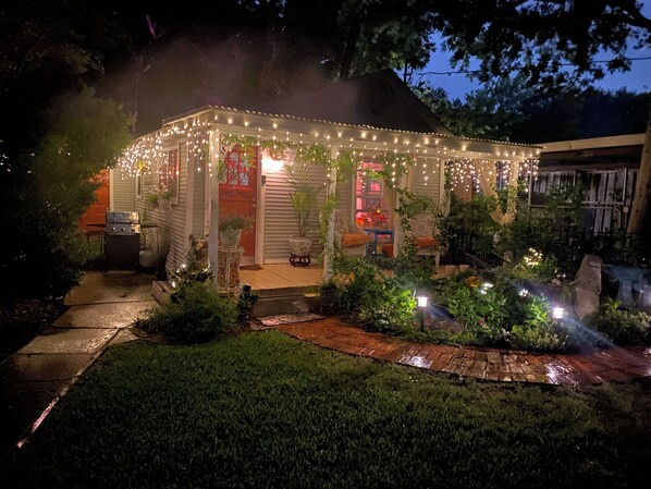 A covered outdoor area with string lights, potted plants, and a grill.