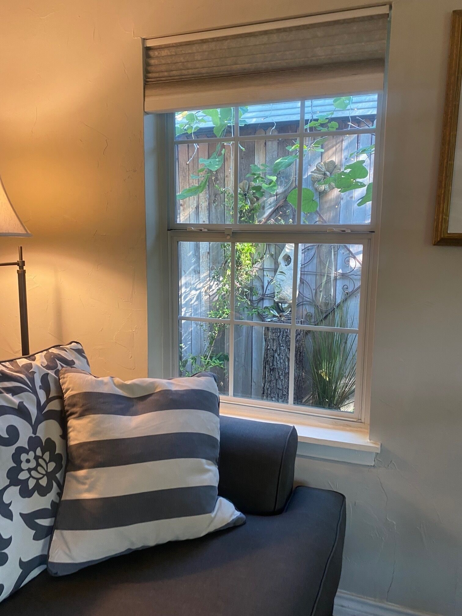 A room with a window, a sofa, and a lamp.