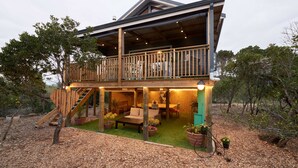 A two-story house with a balcony, outdoor seating area, and a staircase. - Treedom Villas and Vardos (Wilderness)