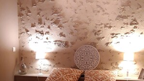 A bedroom with a bed, patterned bedding, a decorative wall, and two bedside lamps. -  comfortable cottages in character farmhouse located in Drôme Provençal (Grillon)
