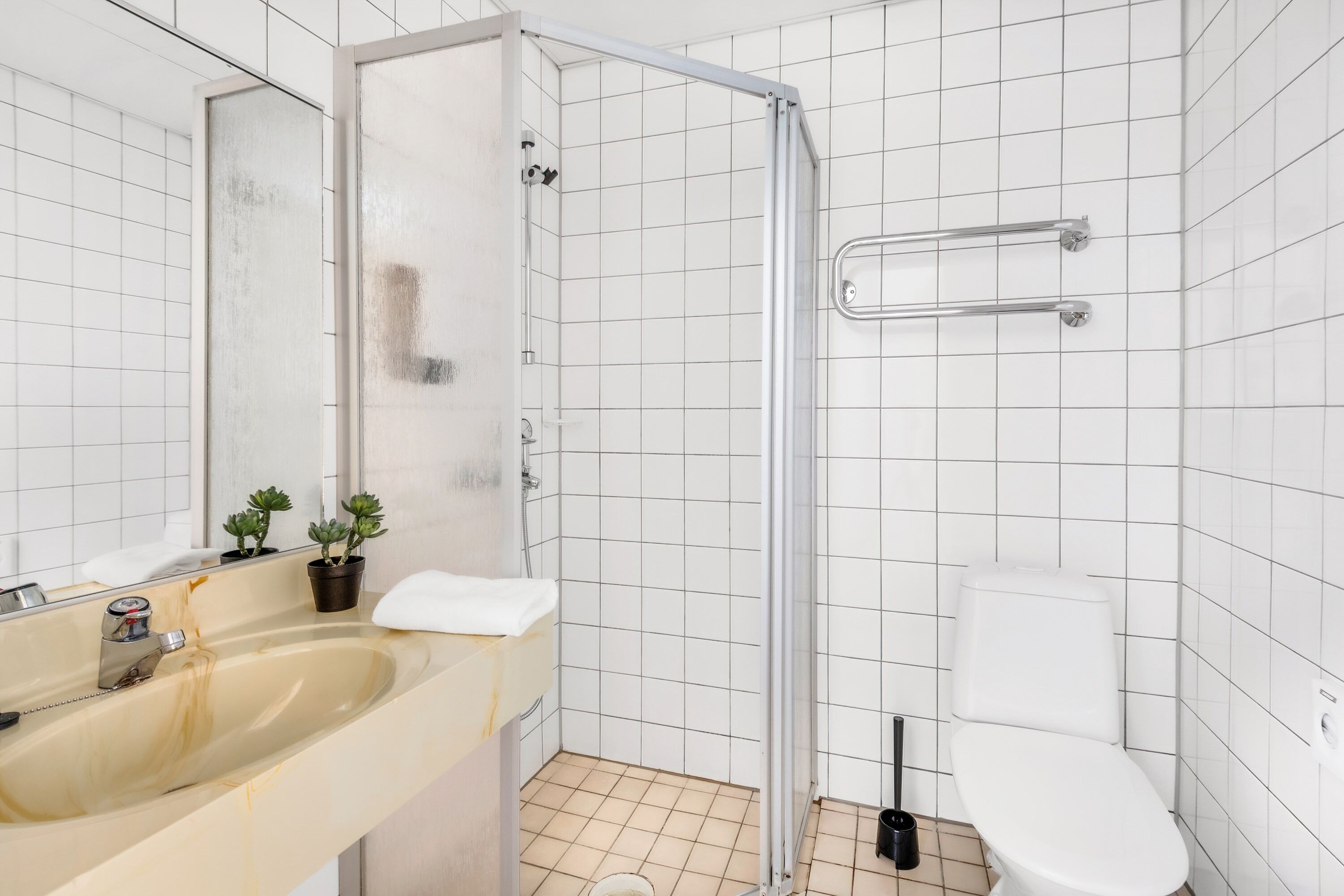 A bathroom with a shower, toilet, sink, and a mirror.