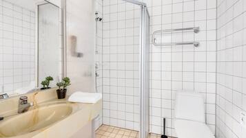 A bathroom with a shower, toilet, sink, and a mirror.