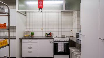 Una cocina compacta con armarios blancos, estufa, horno y microondas.