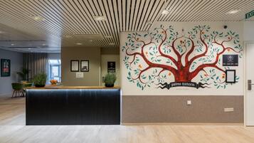 A reception desk with a tree mural, a meeting room sign, and a contact number on the wall.