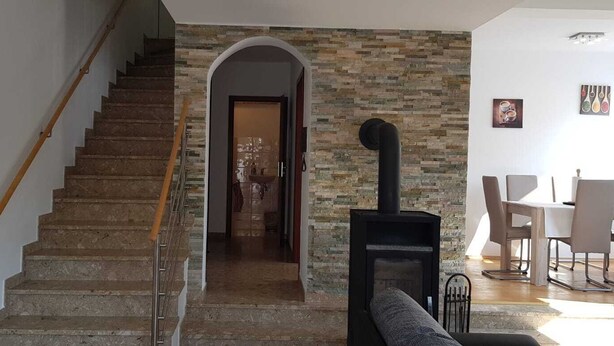 Una escalera conduce a una habitación con pared de piedra y chimenea.
