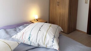 Un dormitorio con una cama, una mesita de noche con lámpara y un armario de madera.
