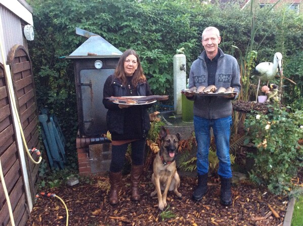 A backyard with a wooden shed, a grill, and a dog. - Apartment Magarete / Detern / Ostfriesland. (Detern)