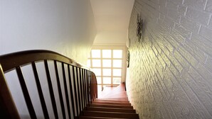 Una escalera con barandilla de madera que conduce a una puerta con diseño de cuadrícula.