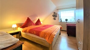 Un dormitorio con cama, una mesita de noche, una ventana con cortinas y un radiador.