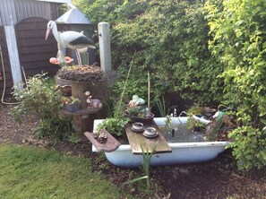 A garden with a pond, a wooden structure, and a statue of a bird. - Apartment Magarete / Detern / Ostfriesland. (Detern)