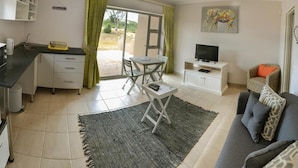 A modern living room with a dining area, a TV, and a sofa. - Sundune Guest House & Self Catering (Colchester)