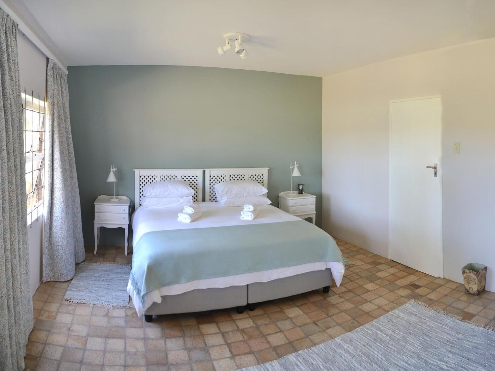 A neatly arranged bedroom with a bed, bedside tables, and a door.