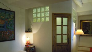 Une chambre à coucher avec un lit, une table de chevet, une lampe, une porte et une fenêtre.