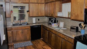 Eine Küche mit Holzausstattung, Granit Arbeitsplatten, einem Geschirrspüler, einer Kaffeemaschine und einem Toaster.