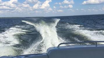 A boat's wake in a body of water with a clear sky and clouds.