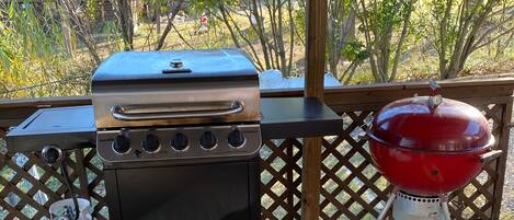 A barbecue grill and a propane tank on a wooden deck.