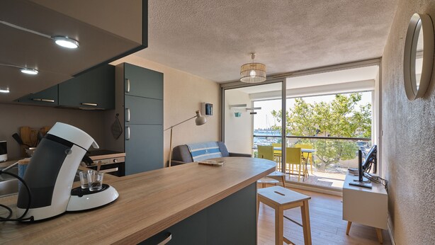 Eine moderne Küche mit Kaffeemaschine, ein Essbereich mit Tisch und Stühlen sowie ein Balkon mit Meerblick.