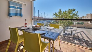 Ein Balkon mit Esstisch für zwei Personen, Blick auf einen Jachthafen mit Booten und Gebäuden.