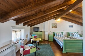 Cozy attic bedroom with two beds, a small table, and a TV.