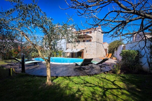 Relax by the pool surrounded by trees and a well-maintained lawn.